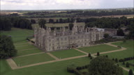 Burghley House Disappear And Reappear Behind Park Trees, Monument And River - Sweeping Shot