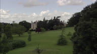 Burghley House Disappear And Reappear Behind Park Trees, Monument And River - Sweeping Shot