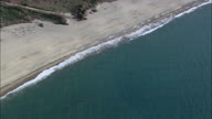 Pull Out From Sandy Calabrian Beach With Polly Tunnels And Greenhouses In The Background